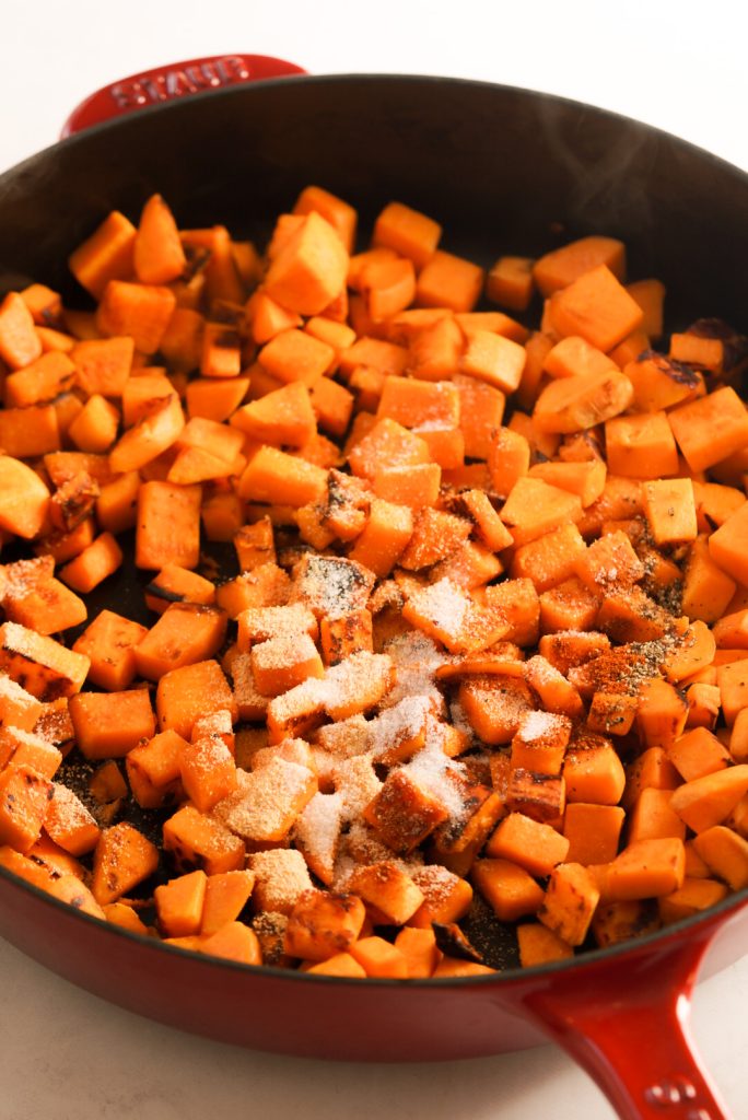 sweet potato pieces with seasonings in a skillet