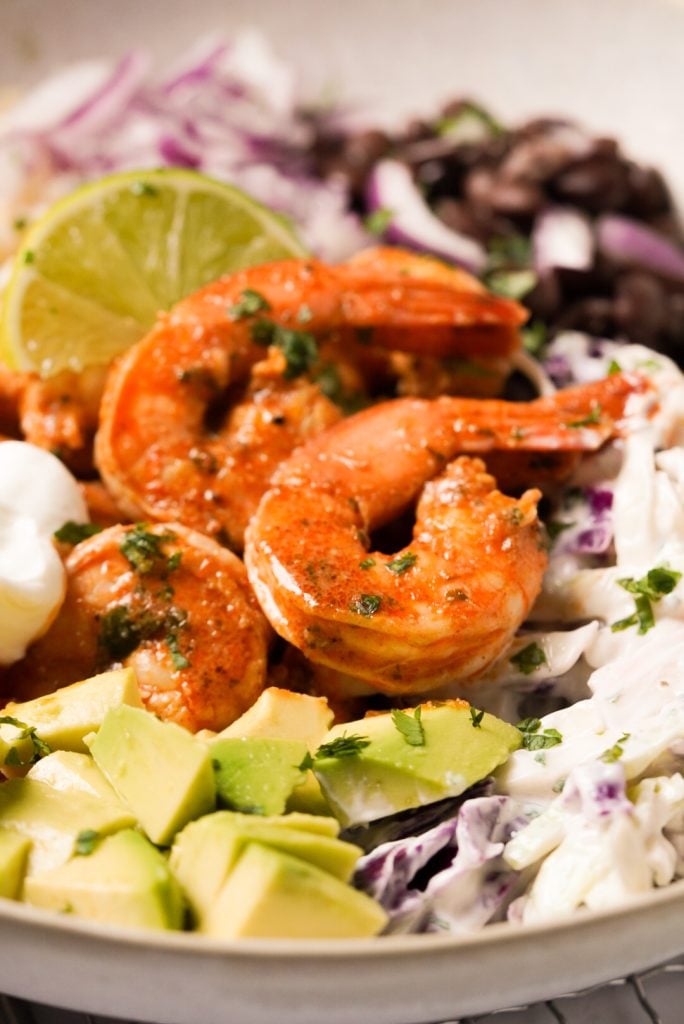 close up shot of seasoned shrimp with crunchy slaw and avocado