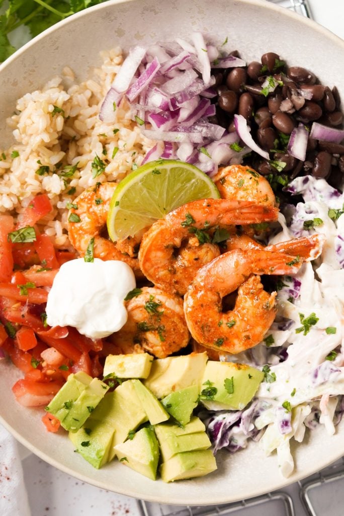 taco bowl with seasoned shrimp, pico de gallo, brown rice, black beans, crunchy slaw, and avocado