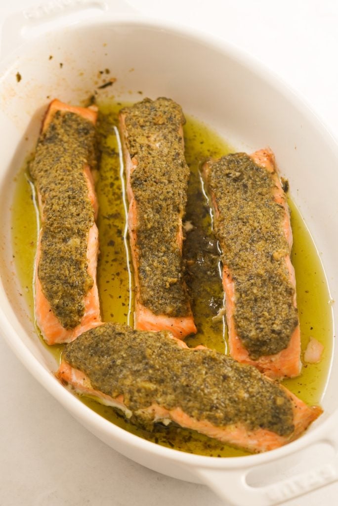 baked salmon topped with a pesto, butter, and parmesan cheese mixture