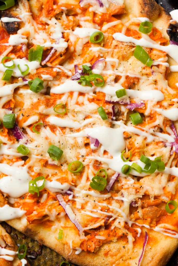 buffalo chicken naan pizza topped with ranch dressing and green onion