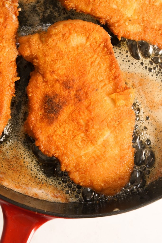 crusted romano chicken in a pan with oil