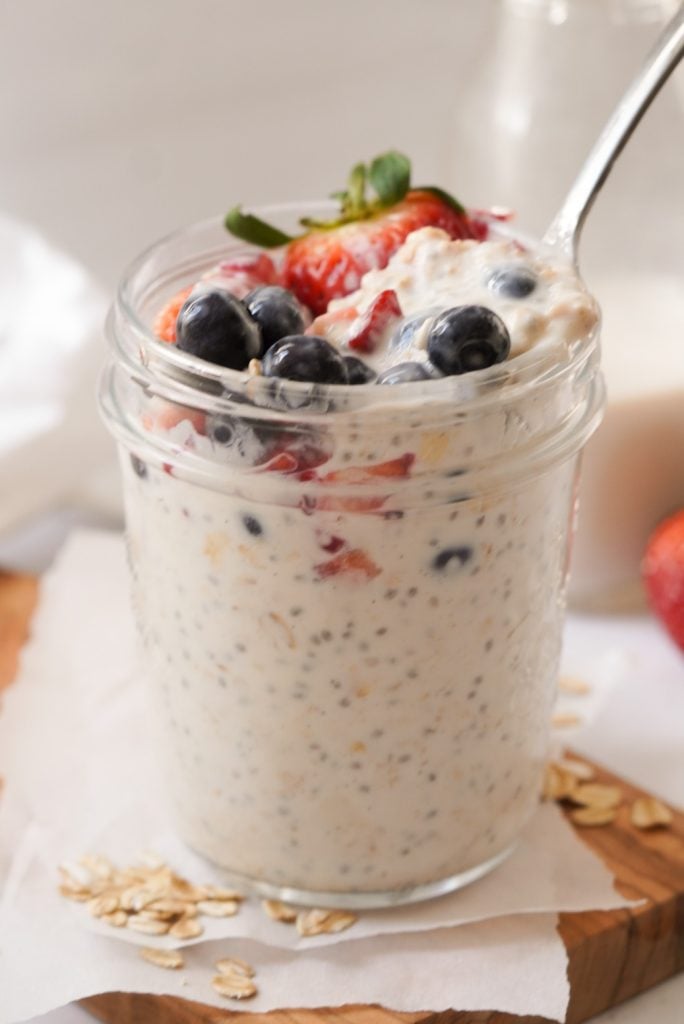 overnight vanilla oats with berries on top and a spoon taking a bite