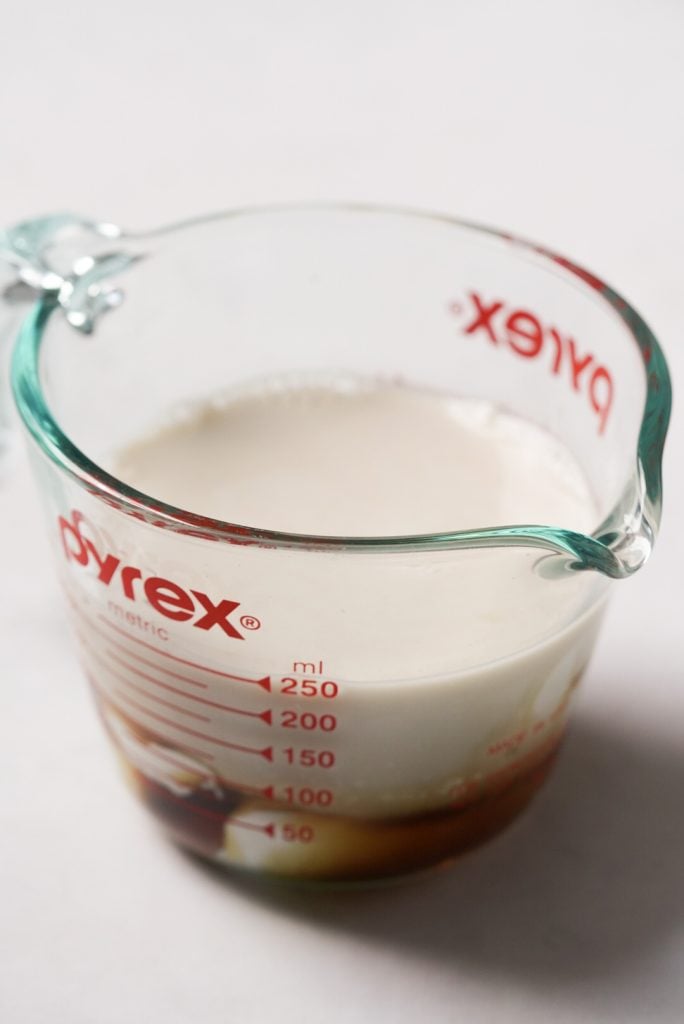 almond milk, greek yogurt, maple syrup, and vanilla extract in a liquid measuring cup
