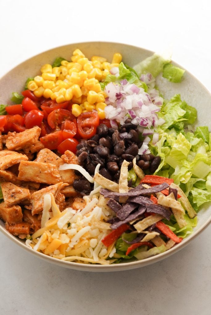 barbecue chicken salad with corn, black beans, cheese, tomatoes, red onion, and tortilla strips