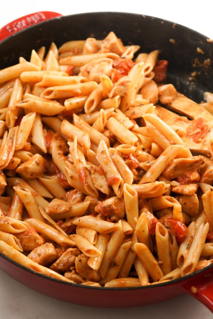tomatoes, pasta, and chicken mixed together in a pan