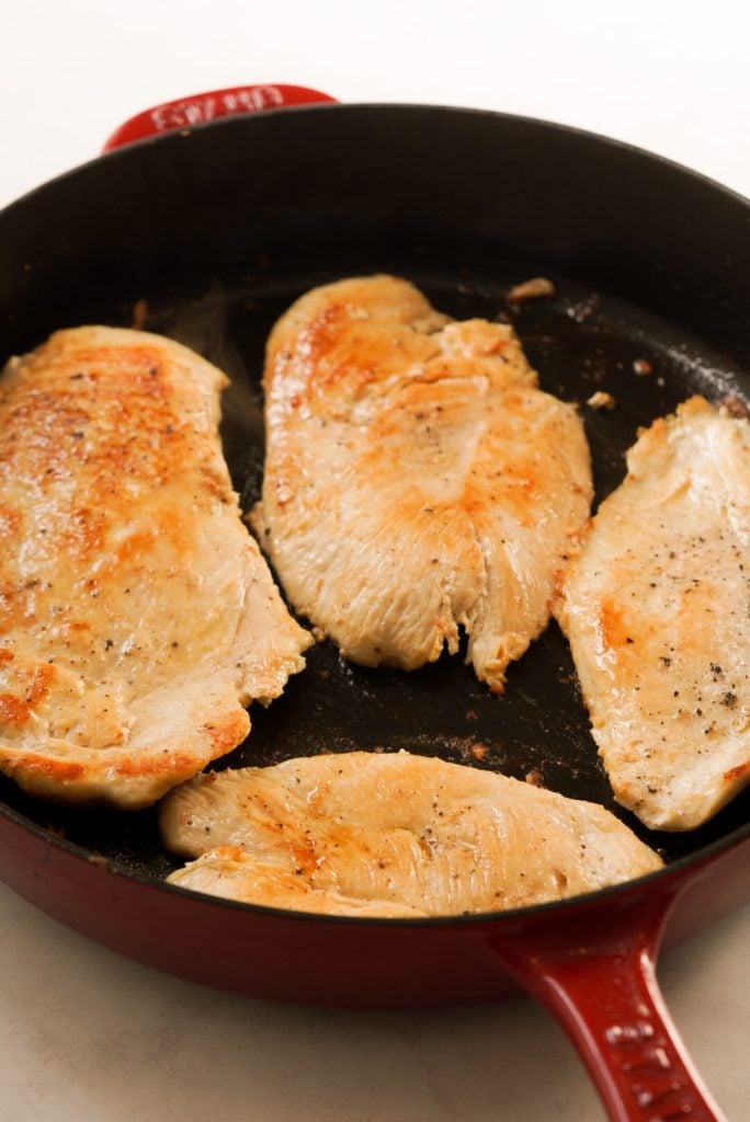 seared thin chicken breasts in a large pan