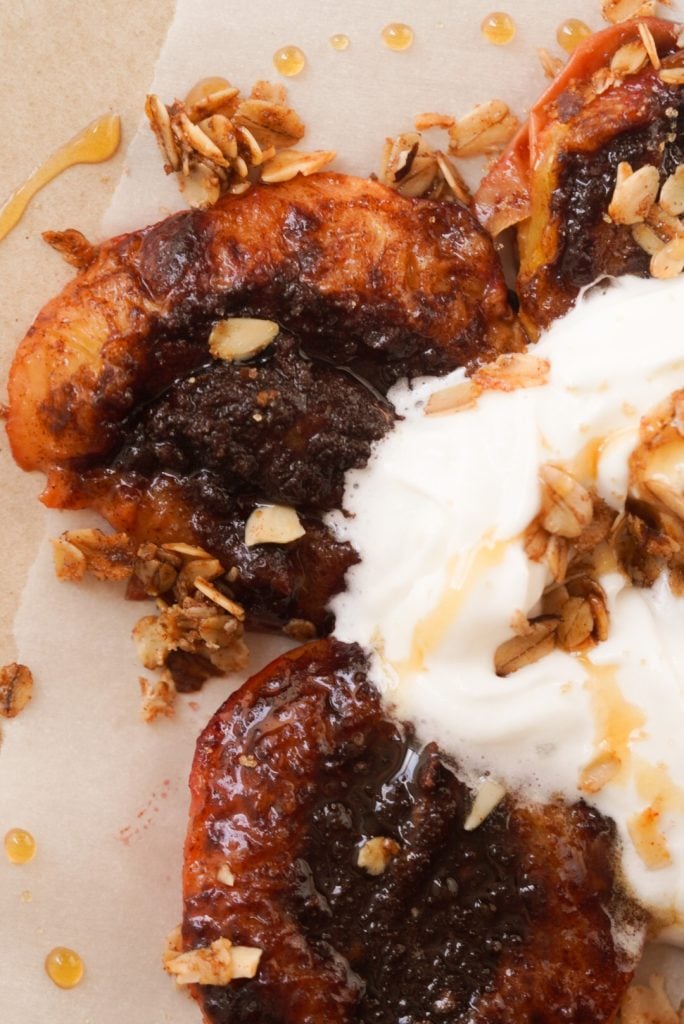 overhead shot of a serving of air fryer peaches topped with a dribble of honey, lightly whipped cream, and cinnamon oat streusel.