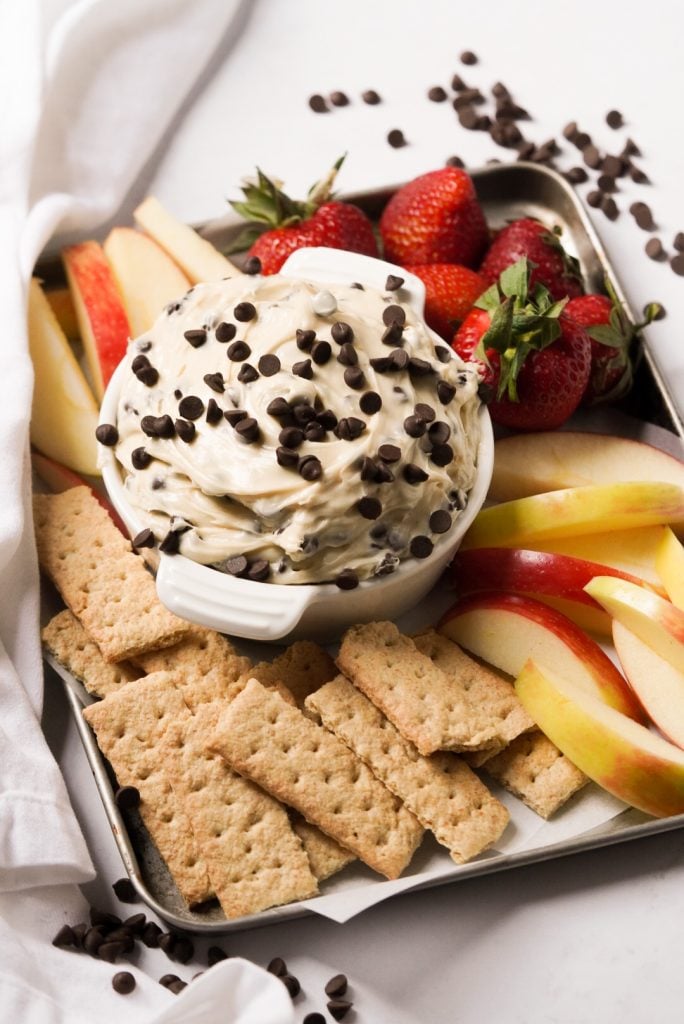 chocolate chip cream cheese dip on a platter with graham crackers, apple slices, and strawberries