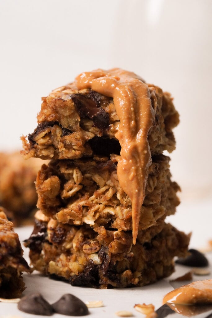 Stack of 3 oatmeal chocolate chip banana bars with a dollop of peanut butter running down the side.