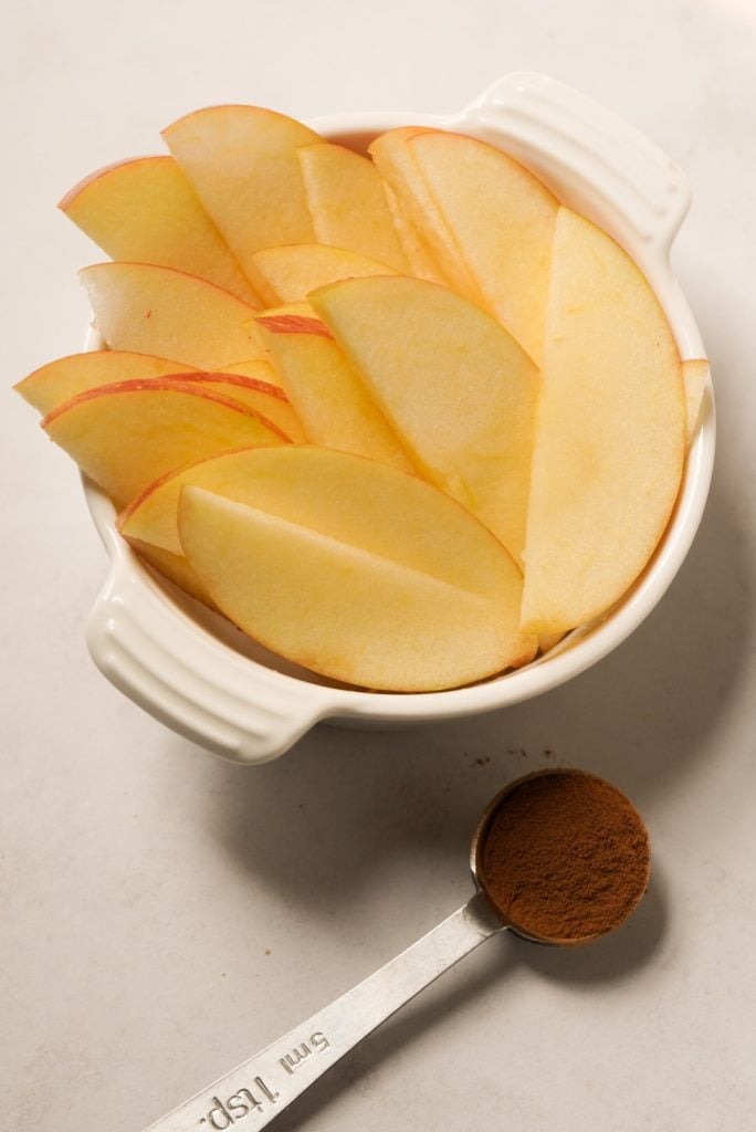 apple slices and cinnamon on a white table