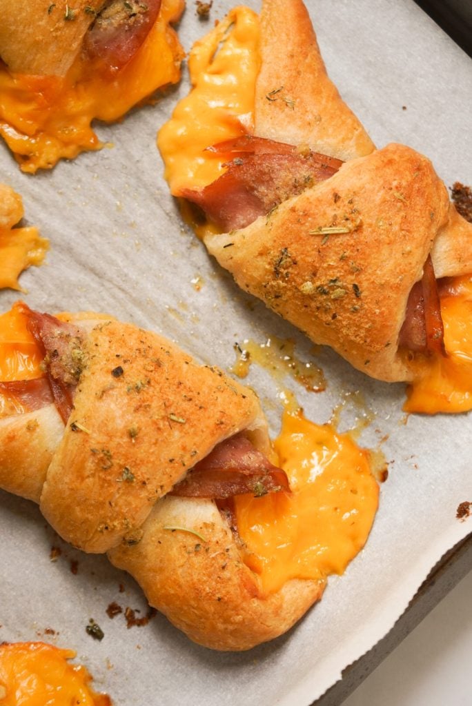 baked cheesy ham crescent rolls on a baking sheet