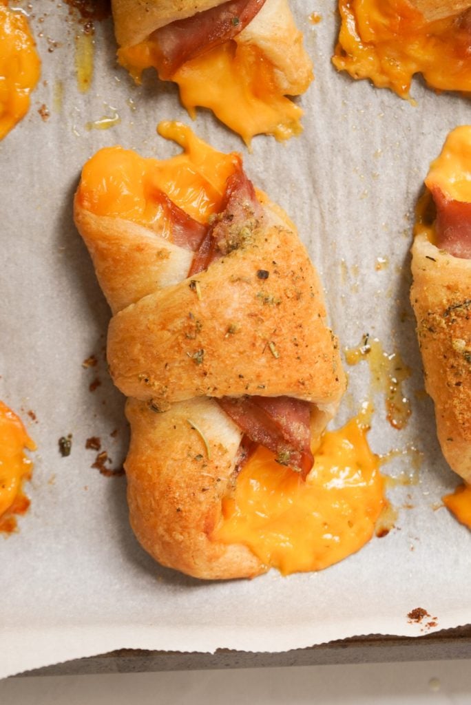 ham and cheese crescent rolls on a parchment paper lined baking sheet