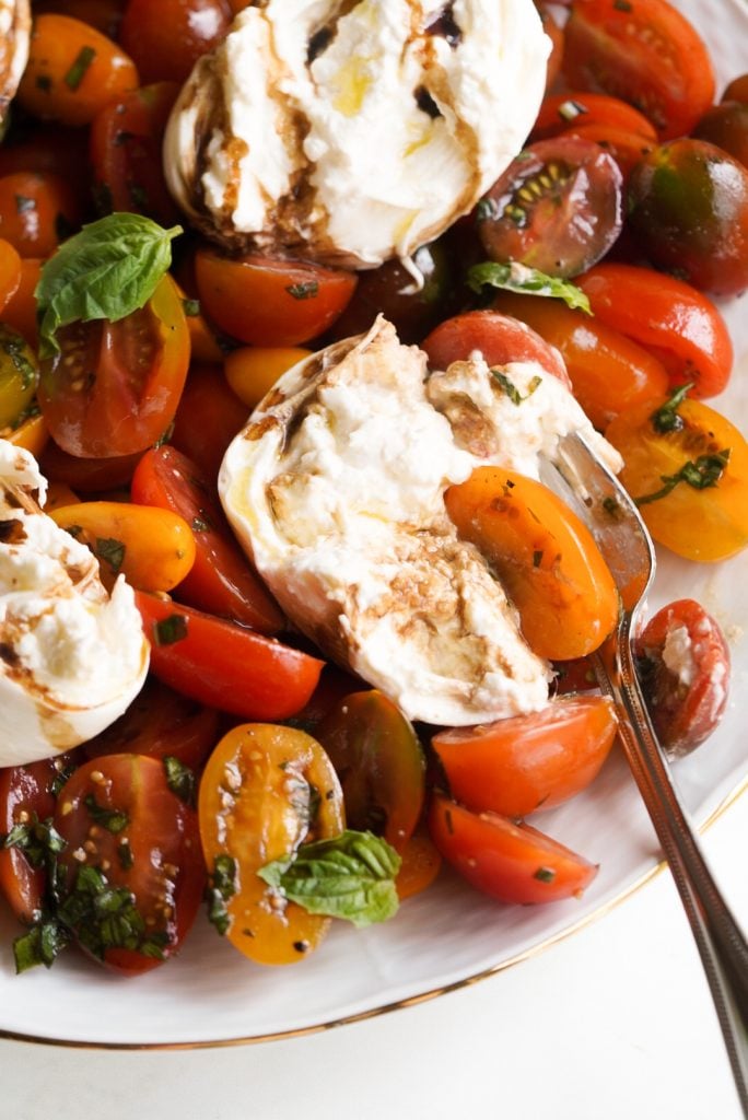 hero shot of a serving platter of tomato caprese salad with fresh burrata.