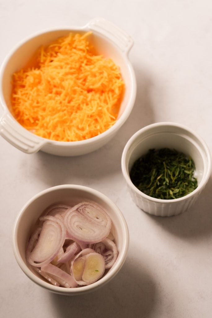 cheddar cheese, shallots, and fresh thyme on a white table