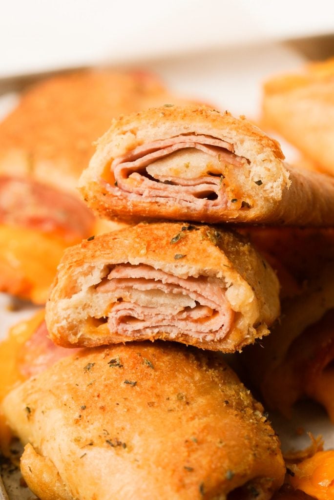 close up shot of a crescent roll with deli ham and cheddar cheese cut in half, showing the inside