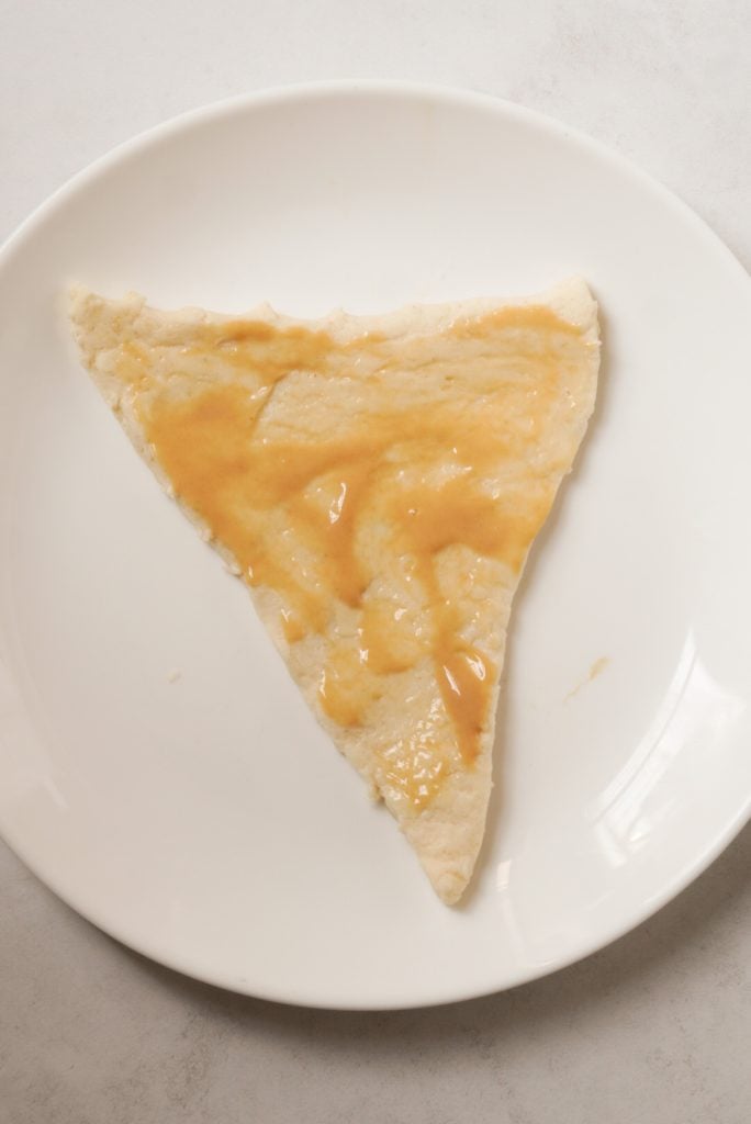 a triangle of crescent roll dough covered with honey mustard