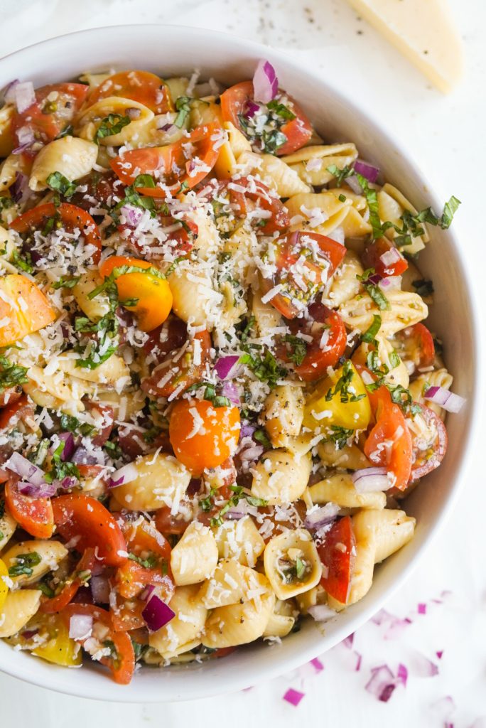 overhead image of cherry tomato pasta salad in a white serving bowl.