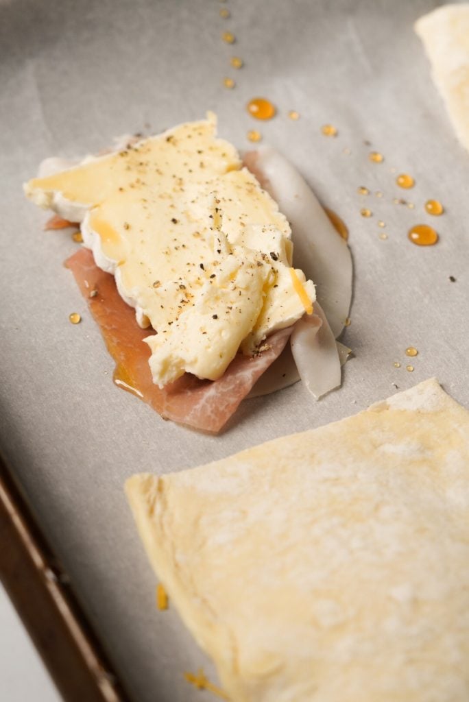 prosciutto, honey, and brie cheese layered on a baking sheet