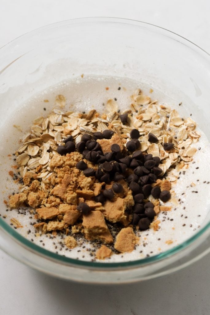 s'mores overnight oats wet ingredients in a mixing bowl with the dry ingredients on top