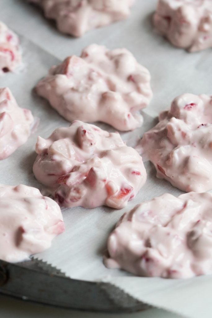 strawberry yogurt clusters on a parchment paper lined baking sheet before freezing