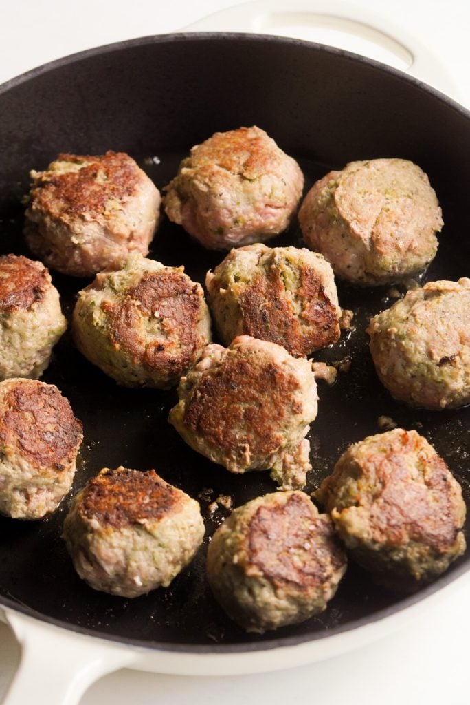 browned turkey meatballs frying in a pan.
