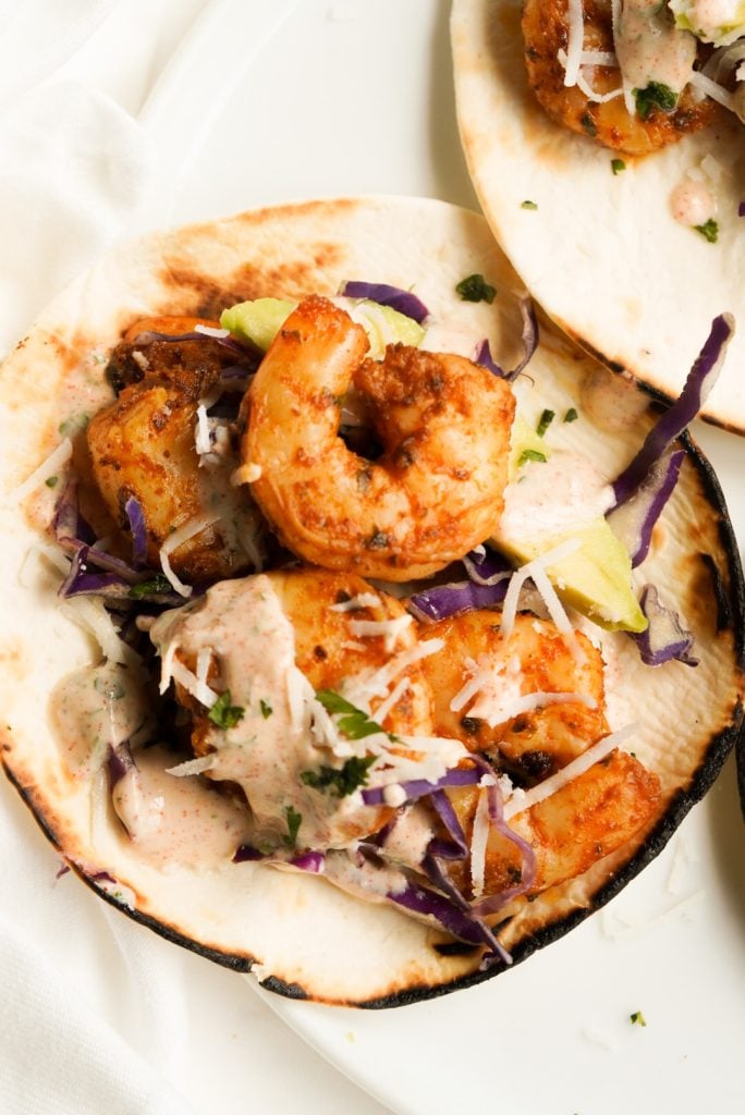 flat lay shot of an assembled baja shrimp street taco with charred tortilla edges.