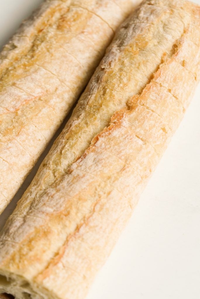 process shot — baguette that has been sliced through like a hasselback potato.
