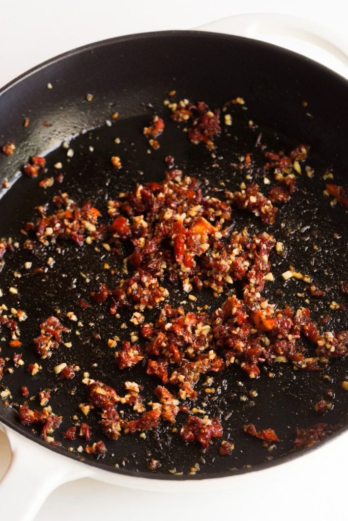 sundried tomatoes and garlic after sautéeing in a skillet.