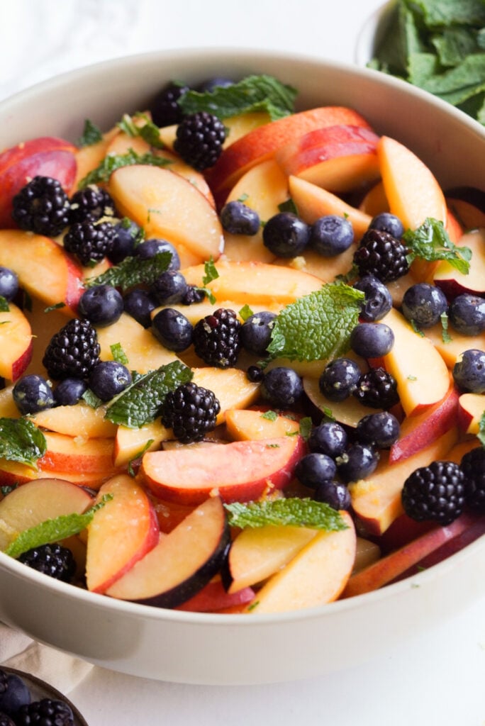 white serving bowl filled with honey lime dressed stone fruit salad.