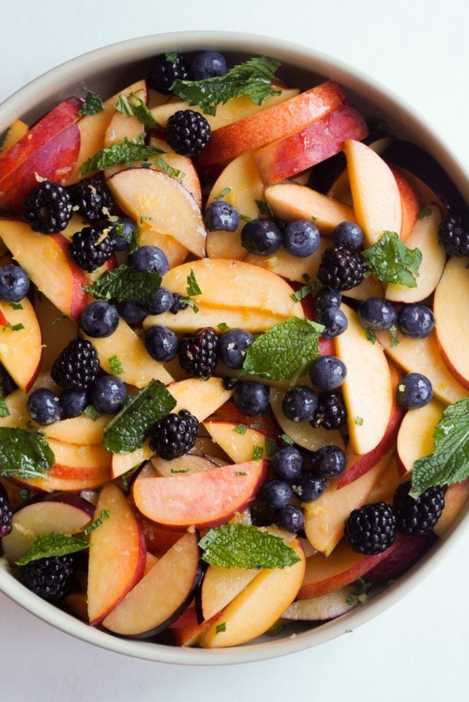 berries and mint added to the sliced peaches, plums, and nectarines in the serving bowl.