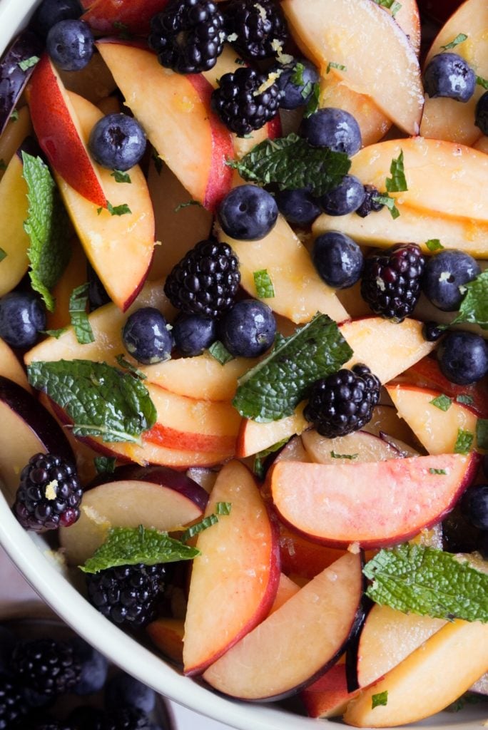 hero shot of minty, lemony stone fruit salad with berries.