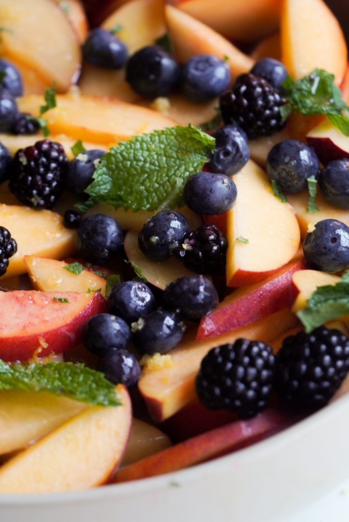 closeup shot of berry stone fruit salad with honey lemon dressing.