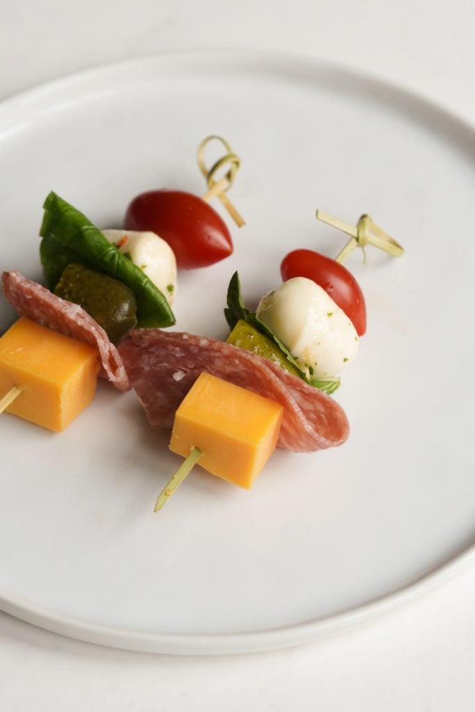 two charcuterie sticks on a white plate