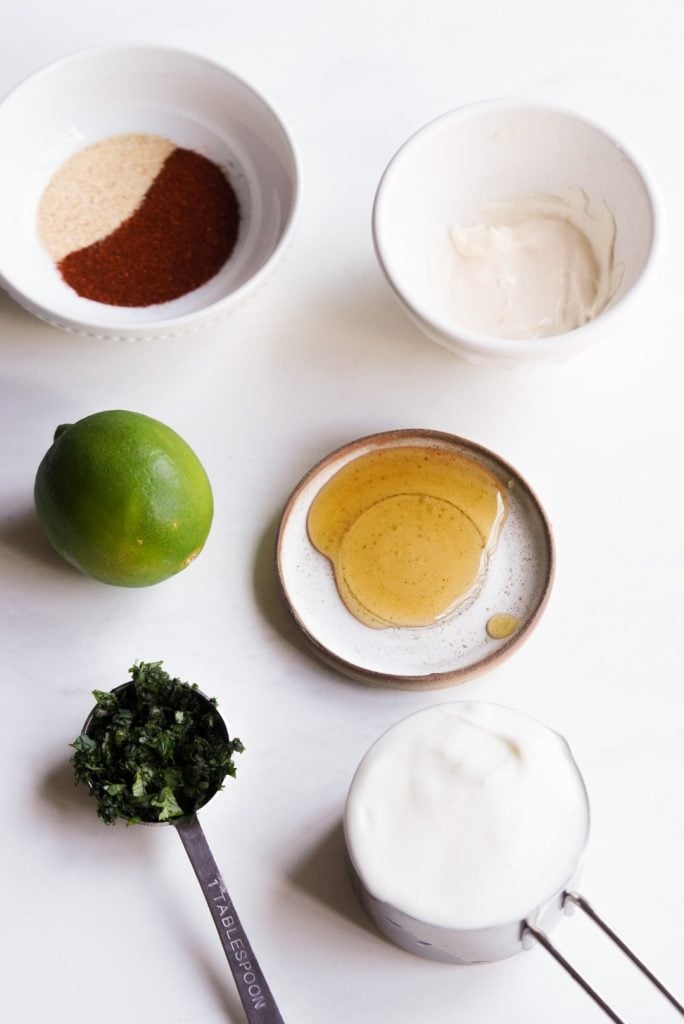 ingredients needed to make the baja shrimp taco sauce (yogurt lime crema) laid out on a white table.