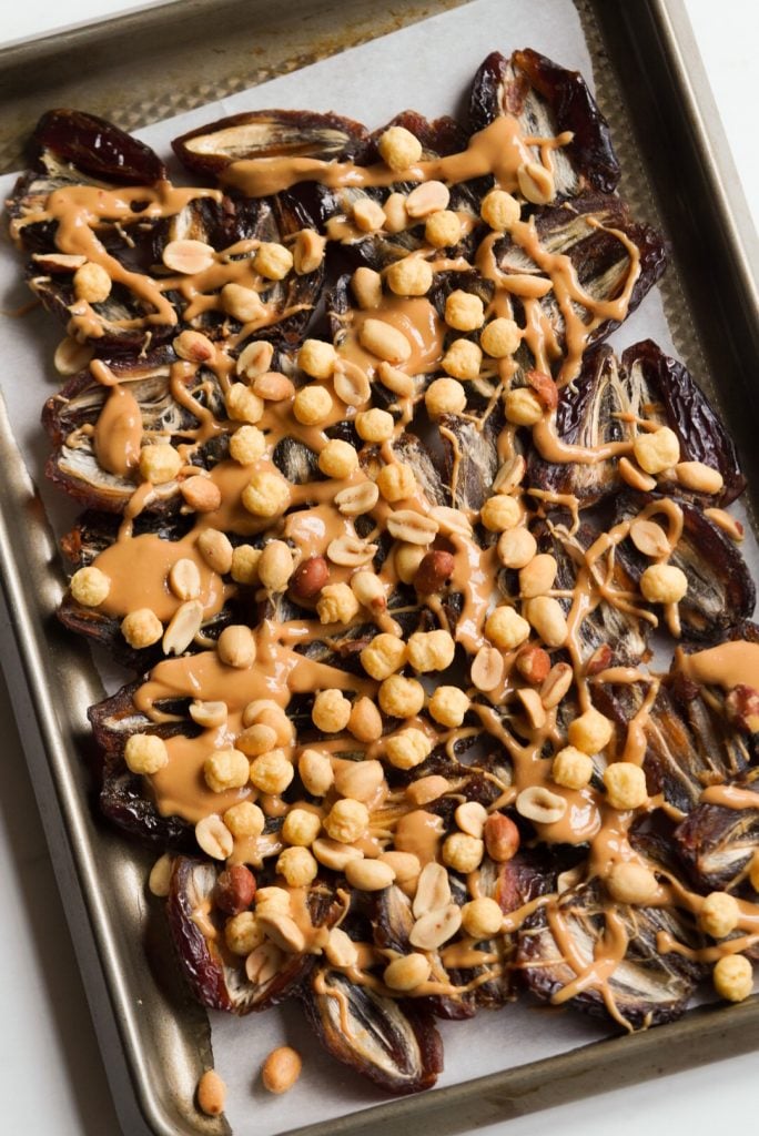 smashed medjool dates with peanuts, cereal, and peanut butter on a baking sheet