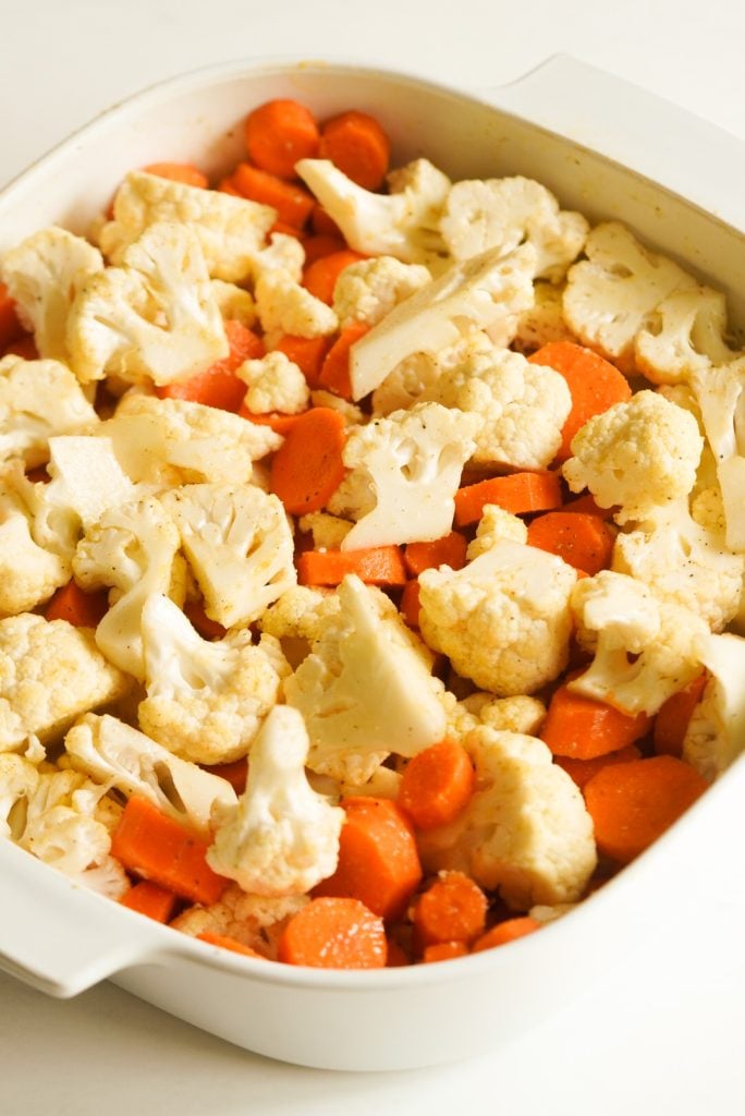 white casserole dish filled with carrot coins and cauliflower florets.