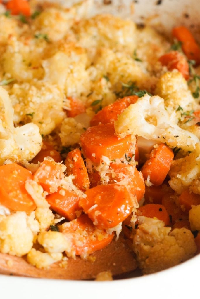 vertical closeup image of roasted cauliflower and carrots with a parmesan herb panko topping.