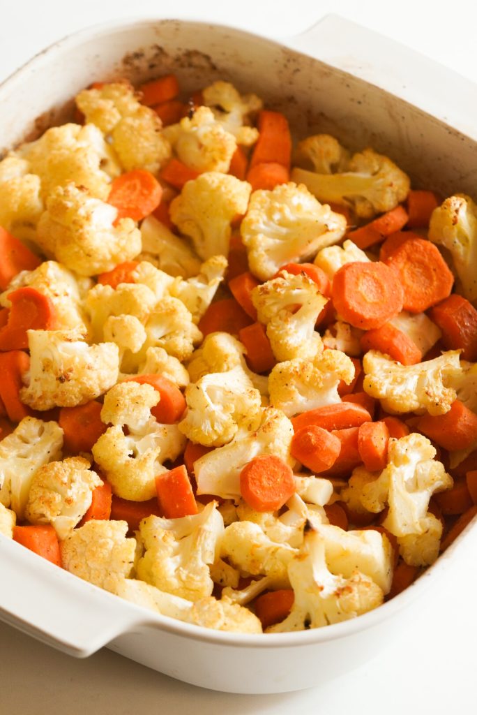 cauliflower and carrots in the white baking dish after roasting until lightly golden.