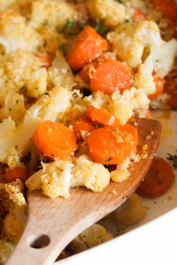 closeup shot of a spoonful of roasted carrots and cauliflower with parmesan and panko topping.