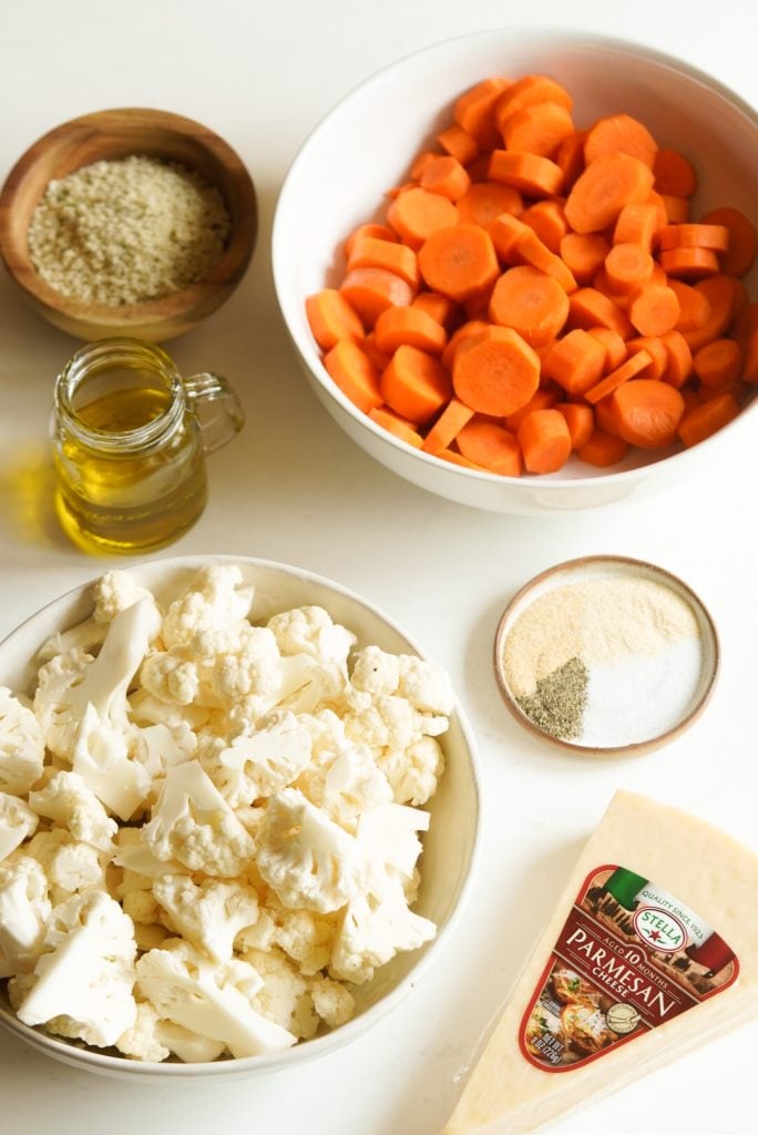 ingredients for making panko parmesan crusted roasted cauliflower and carrots measured out into bowls on a white table.