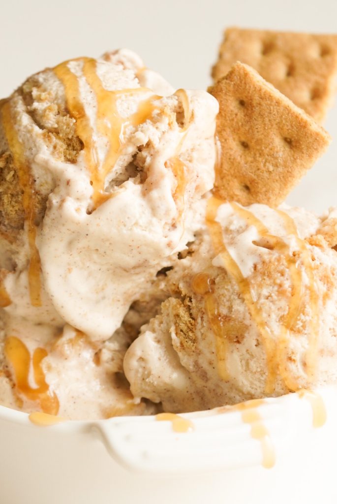 closeup shot of an ice cream sundae made with scoops of no-churn apple crisp ice cream, a drizzle of caramel sauce, and two graham cracker pieces as garnish.