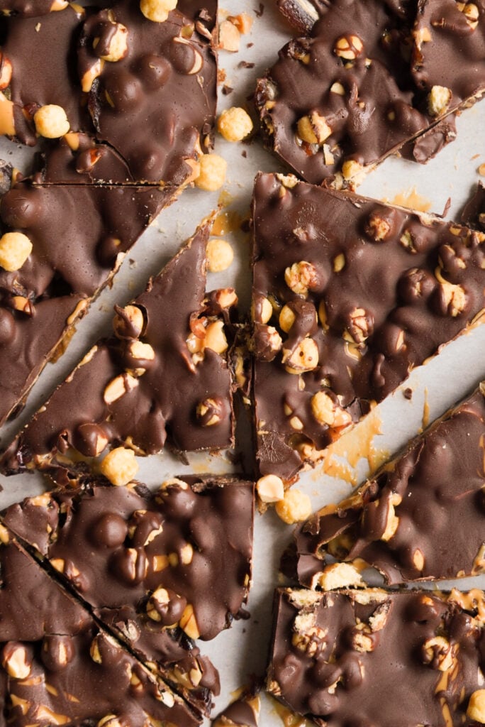 chocolate snickers date bark pieces on a baking sheet