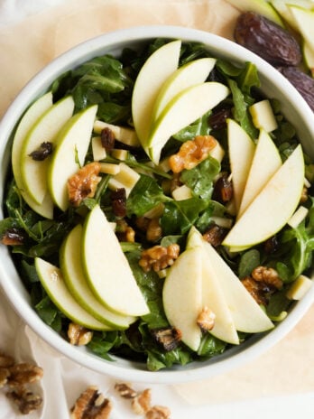 overhead shot of the arugula apple walnut salad with whole dates and walnuts on the table.