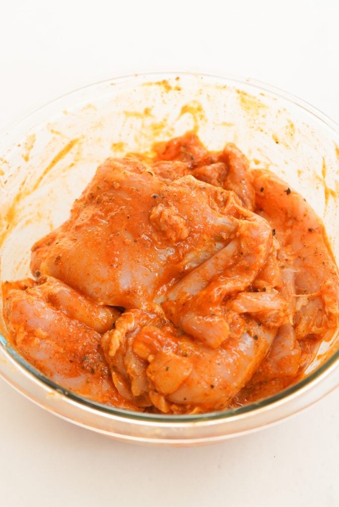 boneless skinless chicken thighs marinating in a buffalo sauce mixture 