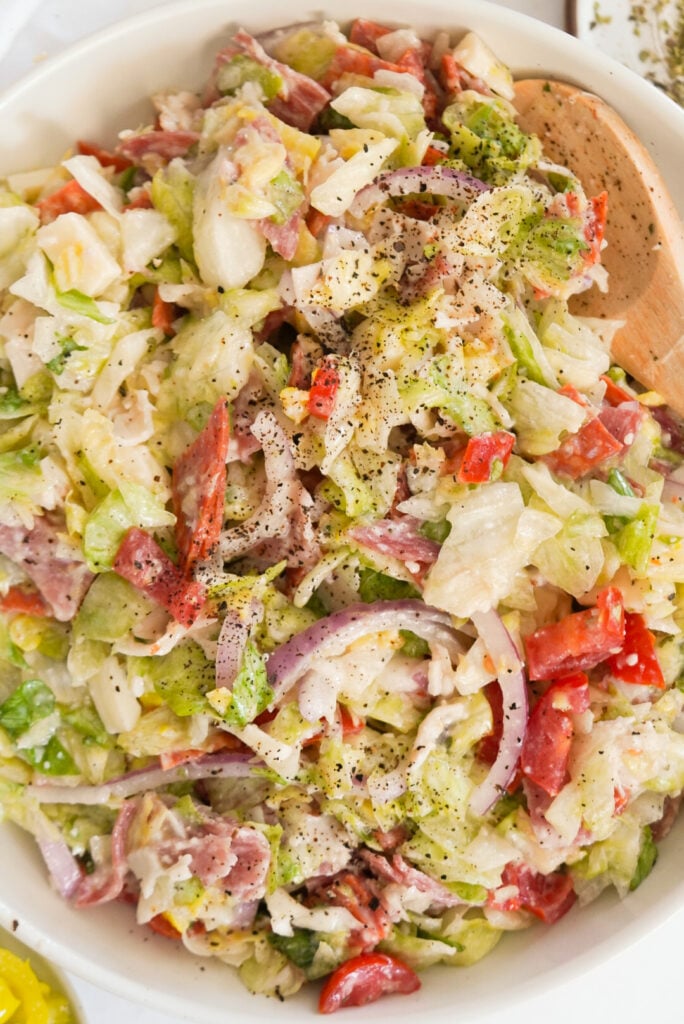 Italian grinder salad in a bowl with a wooden spoon