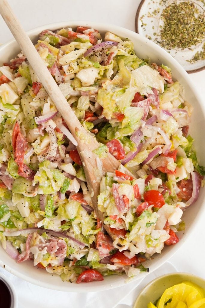 bowl of chopped salad in a large bowl with a wooden spoon