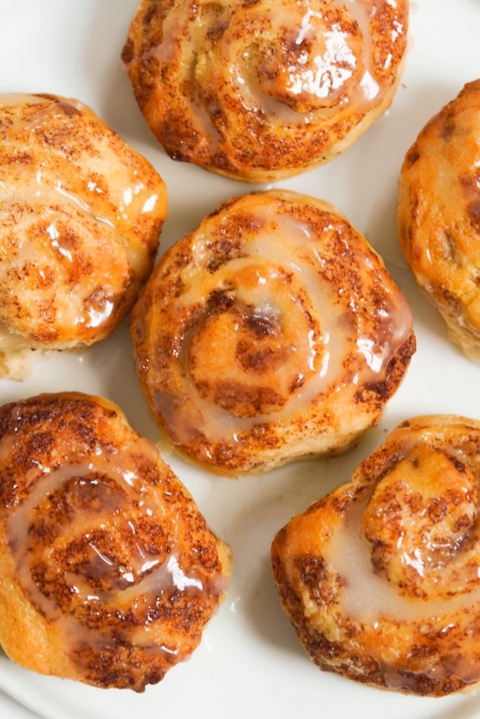 pre-made canned cinnamon rolls on a white plate with icing on top