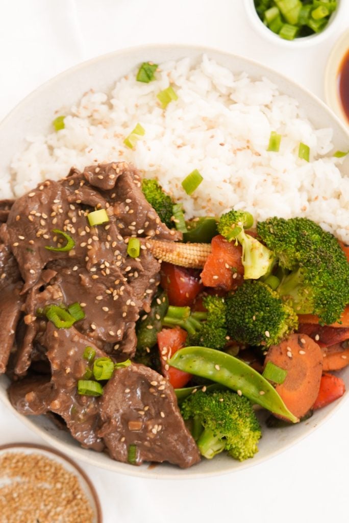 flat lay shot of a white dinner bowl filled with a takeout fakeou dinner of beef with garlic sauce.