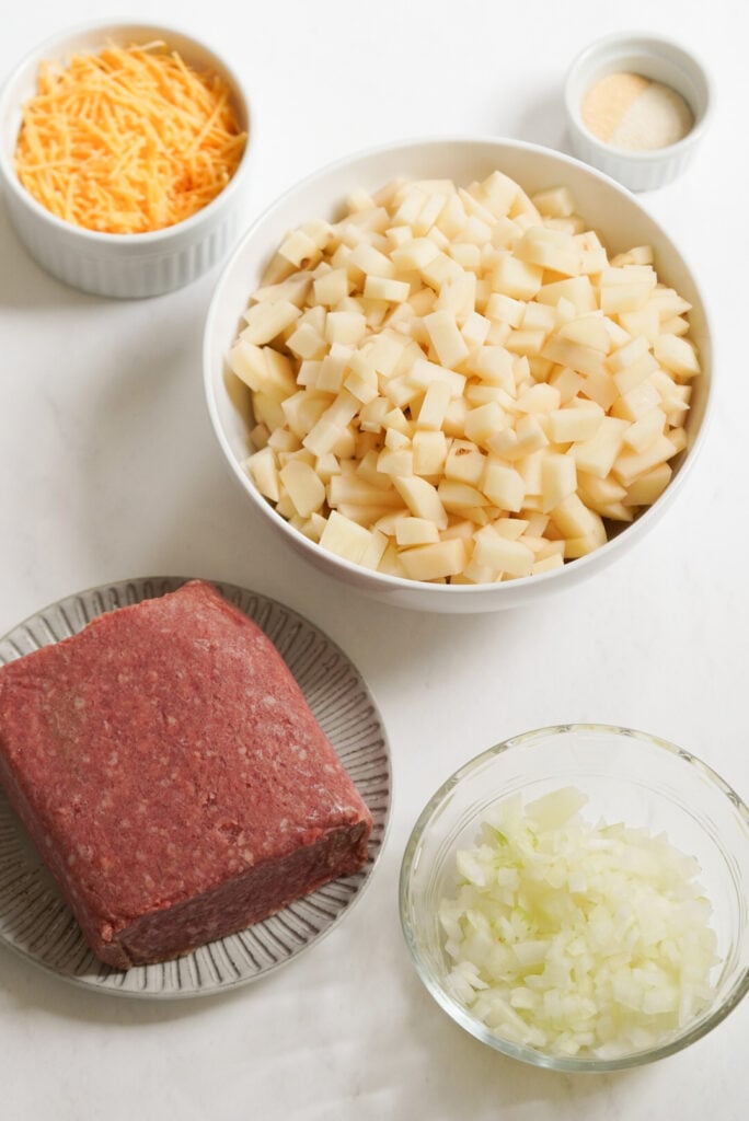 ingredients needed to make big mac hamburger casserole measured out into bowls on a white table.